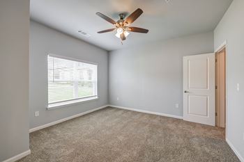 an empty room with a ceiling fan and a window
